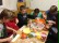 Bild: 5 Schüler*innen sitzen um einen Tisch und schneiden Gemüse klein