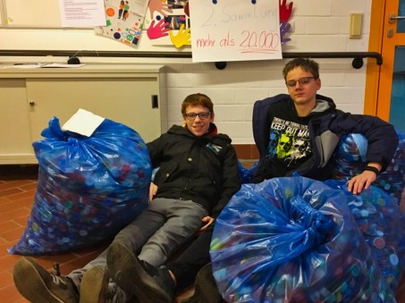 2 Schüler mit Müllsäcken voll mit Plastikverschlüsen.