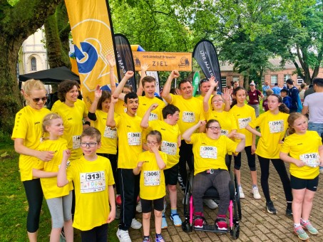 Gruppenbild von Schüler*innen und Erwachsenen. Alle recken die Faust hoch und tragen Laufkleidung.