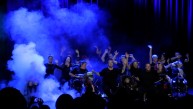 Bild vom Auftritt des Darstellen und Gestalten Kurse. Man sieht ca. 20 Personen, die hälfte sitzt im Rollstuhl. Einige winken mit den Armen. Alle stehen in Bühnennebel und werden durch blaues Licht angestrahlt.