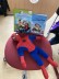 Bild von einer Spiderman Figur. Im Hintergrund stehen 2 Superhelden Bücher.