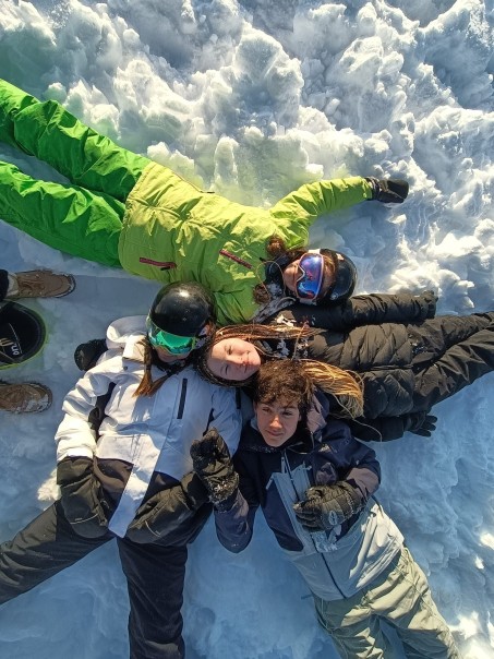 Bild von 4 Personen, die wie eine Windmühle im Schnee liegen.