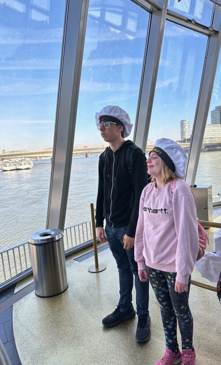 Bild von 2 Schüler*innen. Beide tragen eine typische Kopfbedeckung von Personen, die Schokolade herstellen.