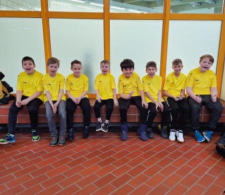 Bild von 8 Sch&uuml;lern in einem Trikot. Sie sitzen nebeneinander und l&auml;cheln.