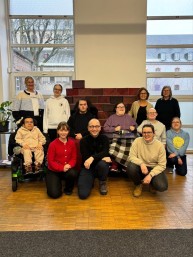 Gruppenbild mit 12 Personen. 3. Personen sitzen im Rollstuhl.
