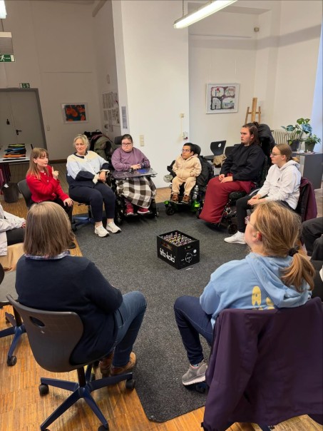 Bild von mehreren Personen die im Kreis sitzen und diskutieren.