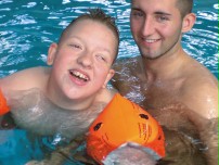 Junger Mann hilft einem Schüler beim Schwimmen