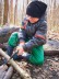 Ein Schüler sägt an einem Ast Totholz im Wald.